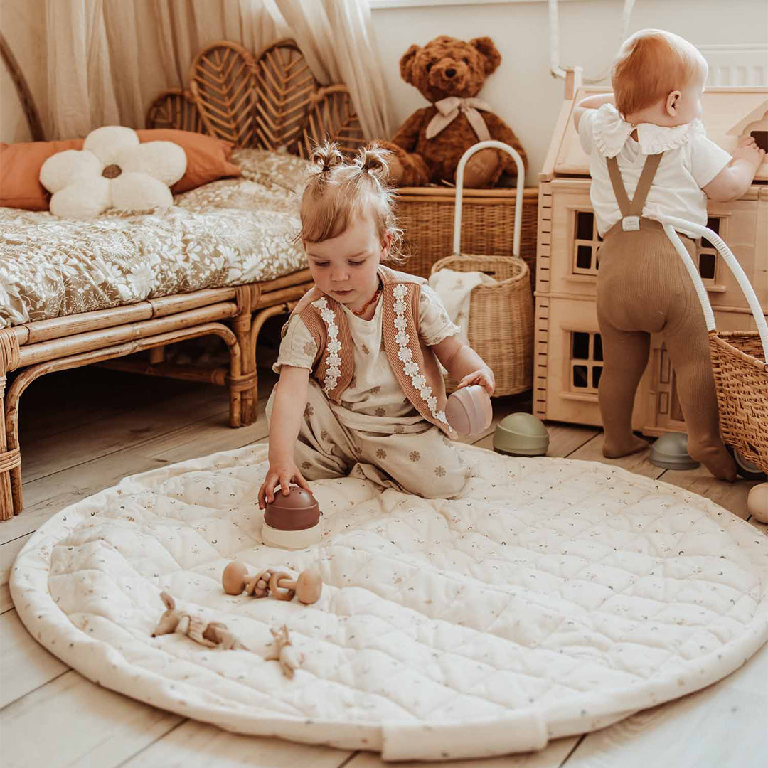 Twee baby's spelen op het play&go ronde babyspeelkleed met maan- en sterrenpatroon in een kinderkamer.
