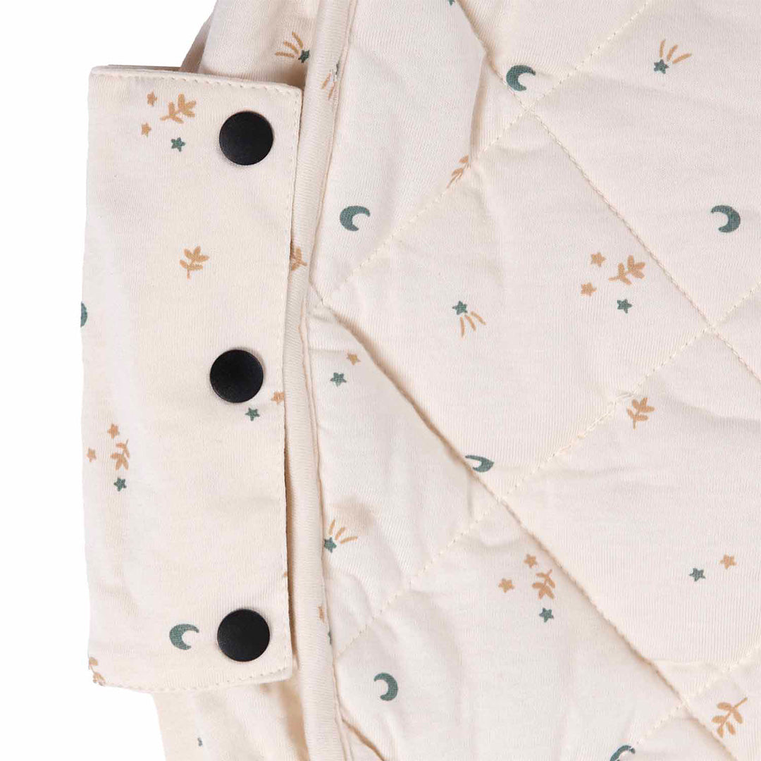 Detail van het beige play&go babyspeelkleed met maan-, sterren- en bladpatroon en zwarte drukknopen.