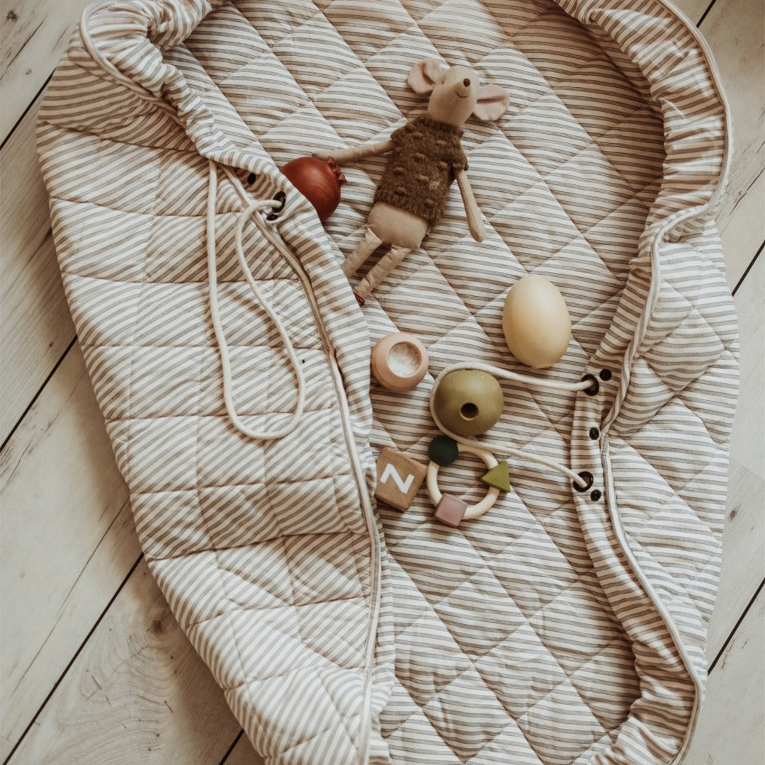 Het gestreepte play&go baby speelkleed is deels samengebonden, met een muis knuffel en babyspeelgoed erop.