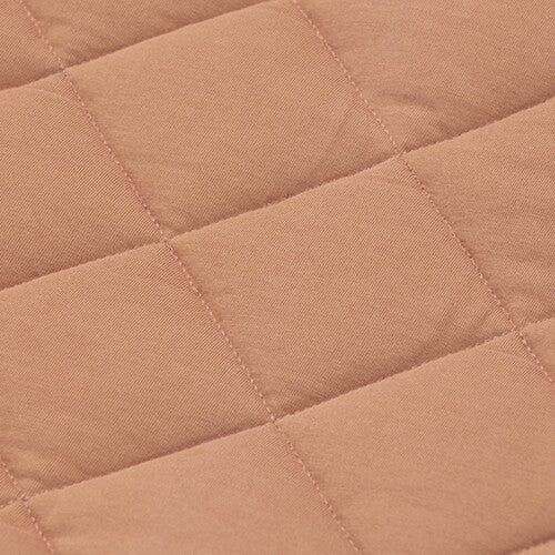 Detail van het gewatteerde tawny bruine katoen-polyester materiaal van het babyspeelkleed.