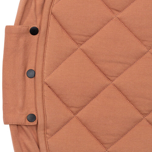 Detail van de rand van het tawny bruine gewatteerde babyspeelkleed met drie zwarte knopen.