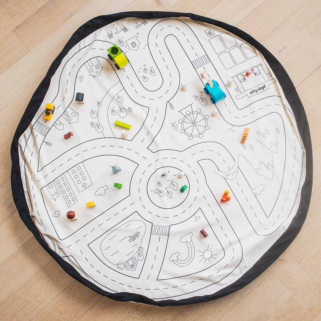 play&go speelkleed met wegenpatroon, volledig uitgespreid op een houten vloer met diverse houten speelgoedjes erop.