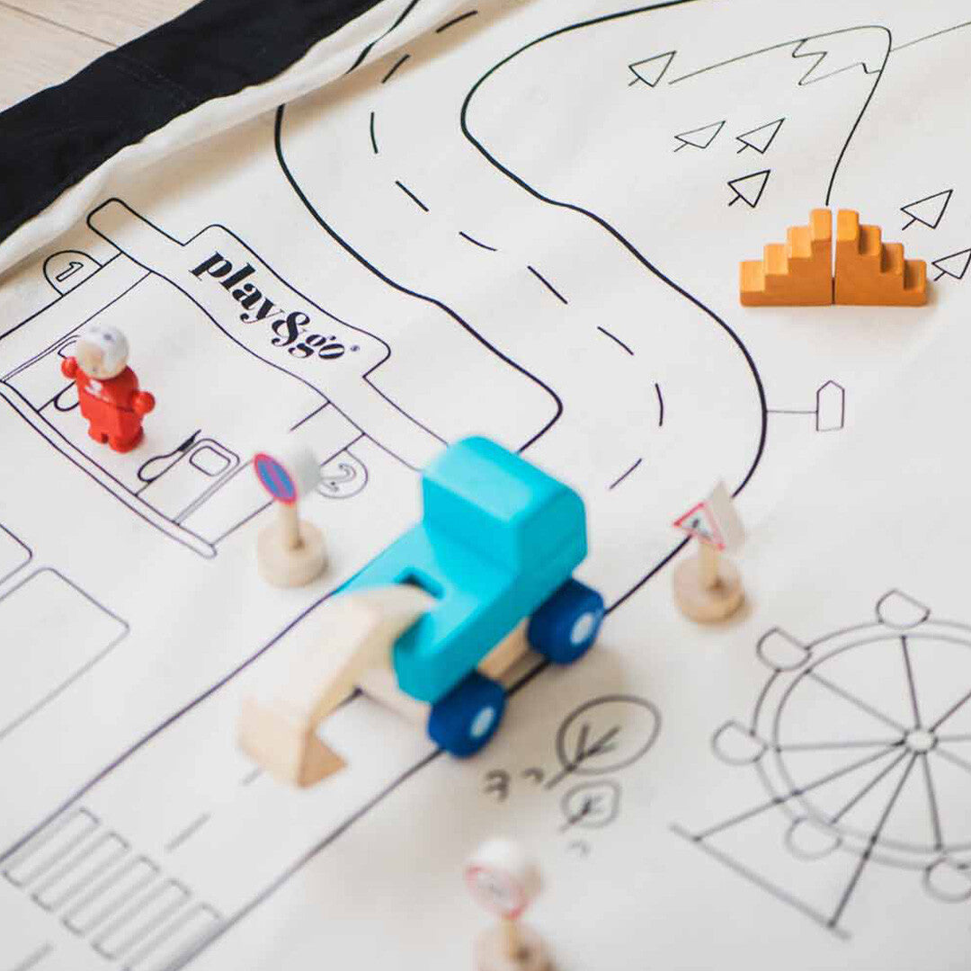 Detail van het play&go speelkleed met wegenpatroon, een tankstation, een houten speelgoedauto en verkeersborden.