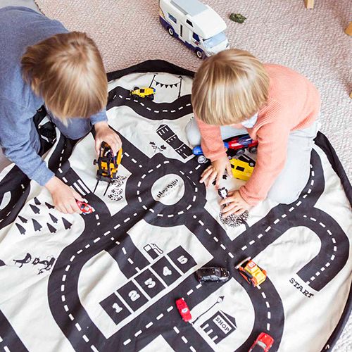 Twee kinderen spelen met speelgoedauto's op het play&go speelkleed met roadmap patroon.