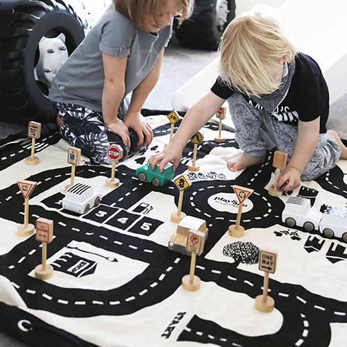 Twee kinderen spelen met auto's en verkeersborden op het play&go speelkleed met roadmap patroon.