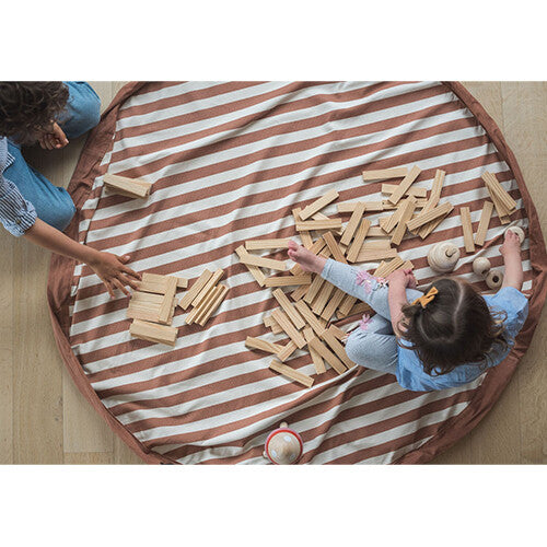 Twee kinderen spelen met houten speelgoed op het open, bruin-wit gestreepte speelkleed.