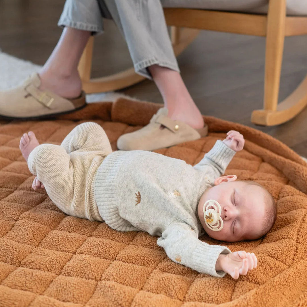 Een slapende baby ligt op het bruine teddy speelkleed van play&go.