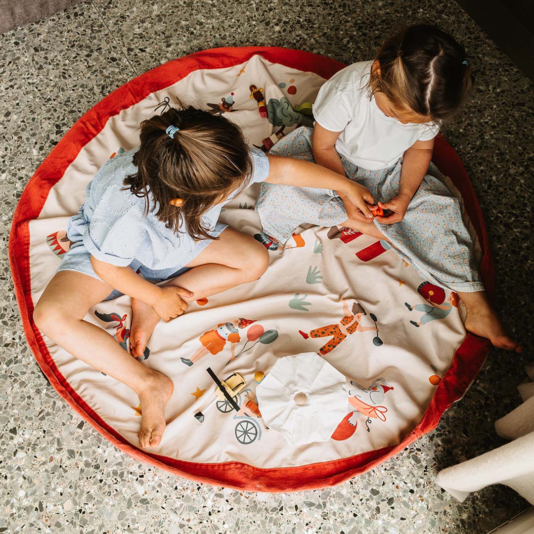 Twee kinderen spelen op een opengevouwen play&go speelkleed met circus thema.