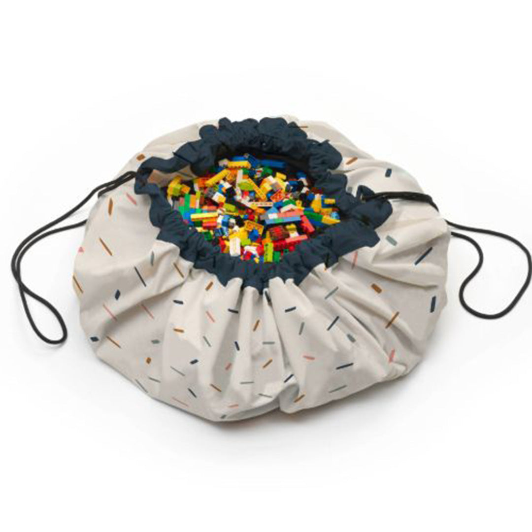 play&go speelkleed en opbergzak met confetti-patroon, gevuld met kleurrijke bouwblokken.