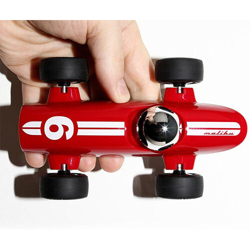 Een hand houdt de Playforever rode raceauto met nummer 6 en 'malibu' tekst van bovenaf vast.