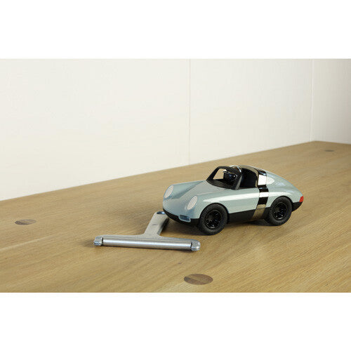 Playforever speelgoedauto op een houten tafel naast een zilverkleurig gereedschap.