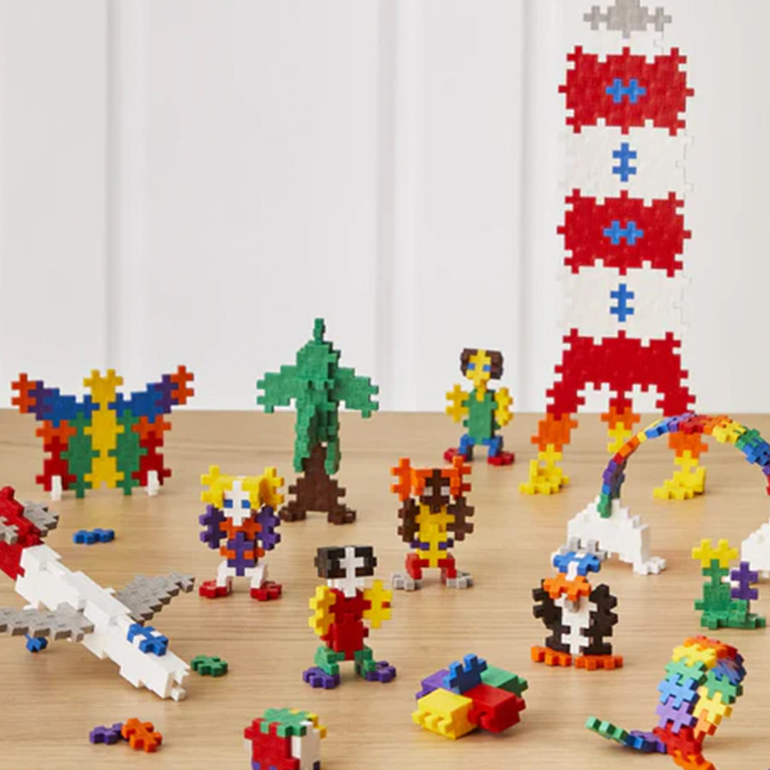 Diverse veelkleurige creaties van Plus-Plus bouwblokken, waaronder een raket, vlinder en vliegtuig.