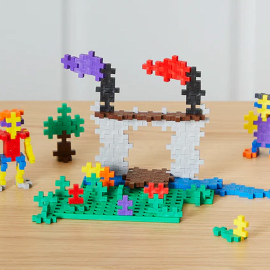 Een landschap met een brug, water, bomen en figuren, gebouwd met veelkleurige Plus-Plus bouwblokken.
