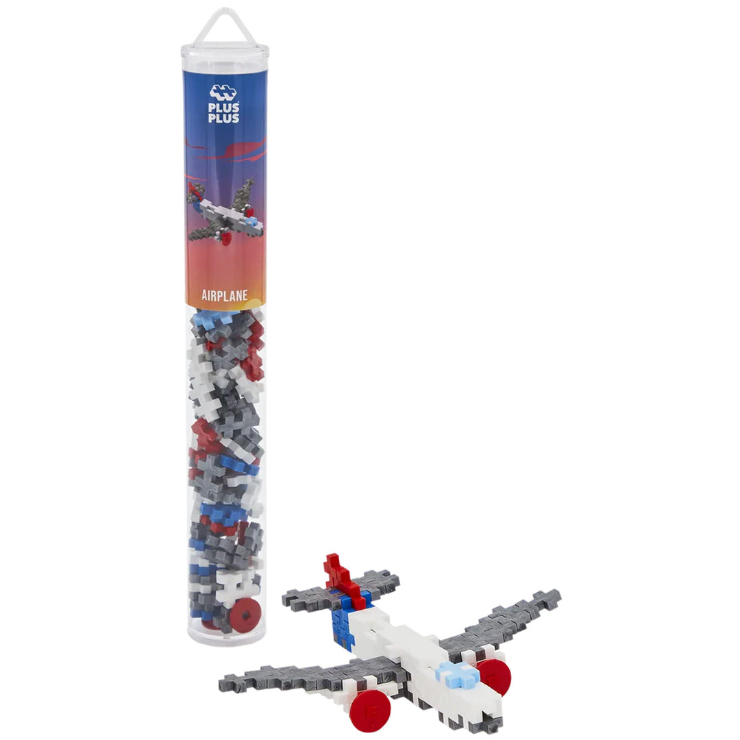 Plus-Plus bouwspeelgoed in een tube met een gebouwd vliegtuigmodel ernaast.