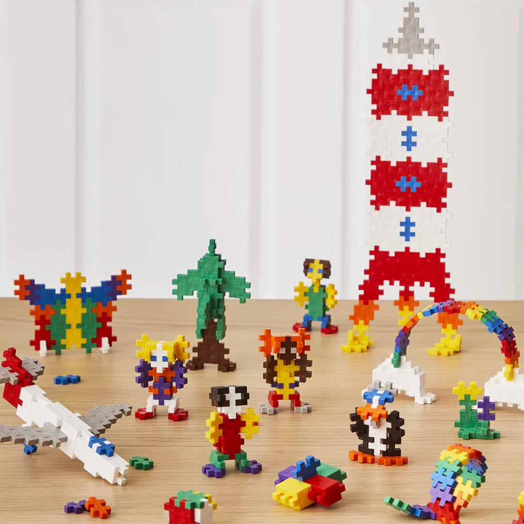 Diverse figuren en objecten, zoals een raket en vliegtuig, gebouwd met veelkleurige Plus-Plus bouwblokken.