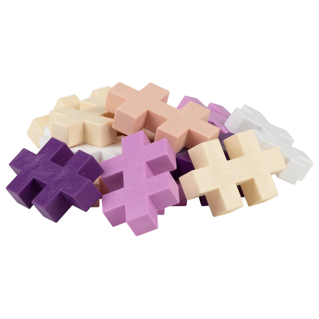 Een hoop losse Plus-Plus BIG bouwblokken in verschillende pastelkleuren.