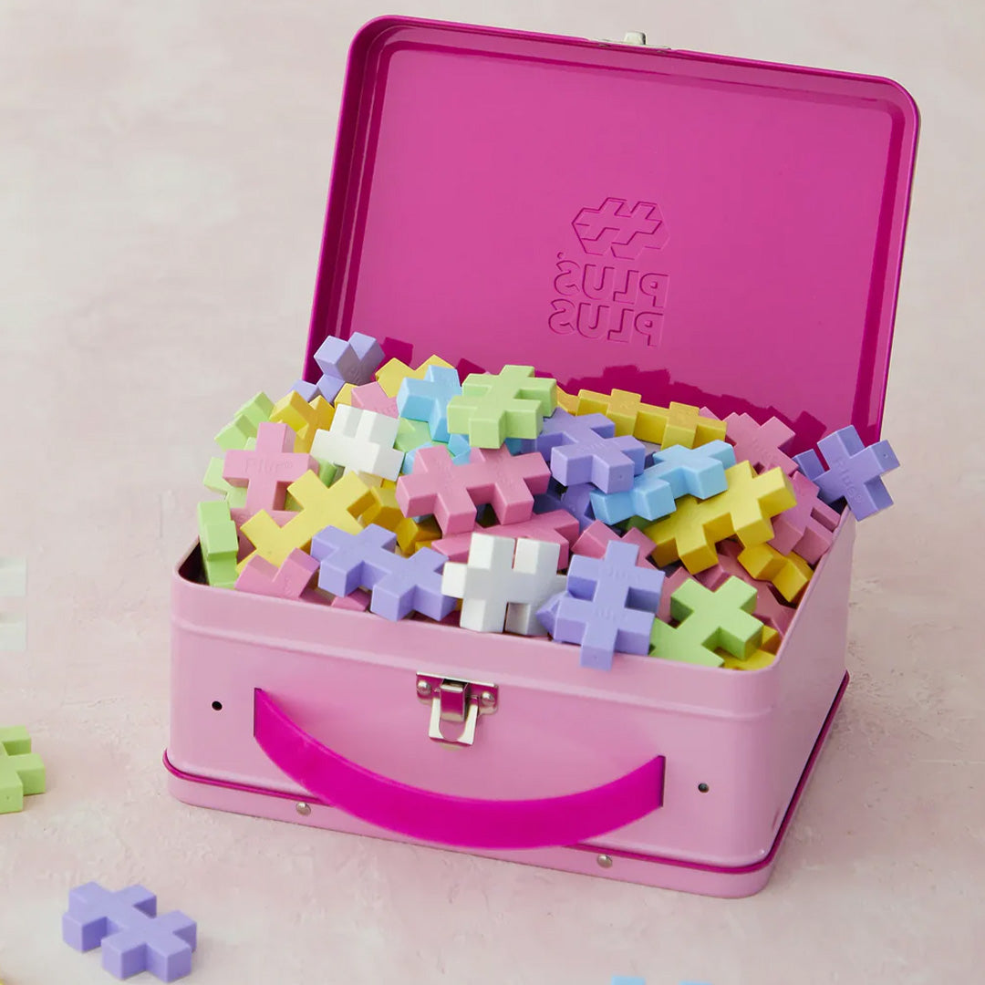 Een open roze metalen koffer van Plus-Plus is gevuld met pastelkleurige bouwblokken.