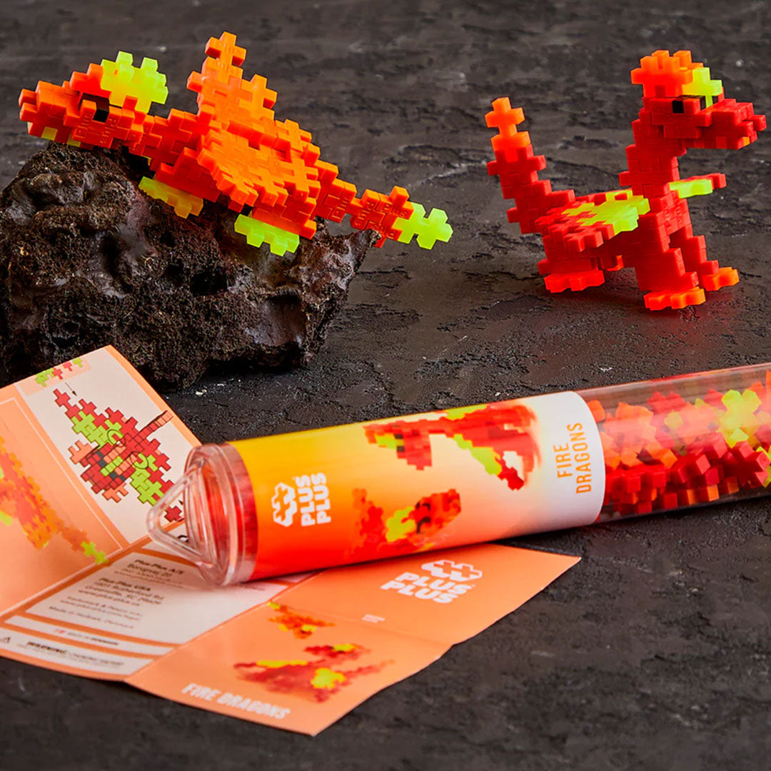 Twee Plus-Plus Fire Dragons figuren van bouwstenen, een vliegende en een staande, met de verpakking en instructies ernaast.