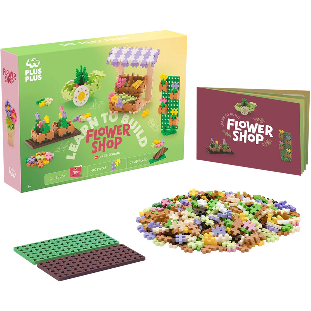 De Plus-Plus 'Learn to Build Flower Shop' set met verpakking, losse bouwblokken, twee bouwplaten en een instructieboekje.