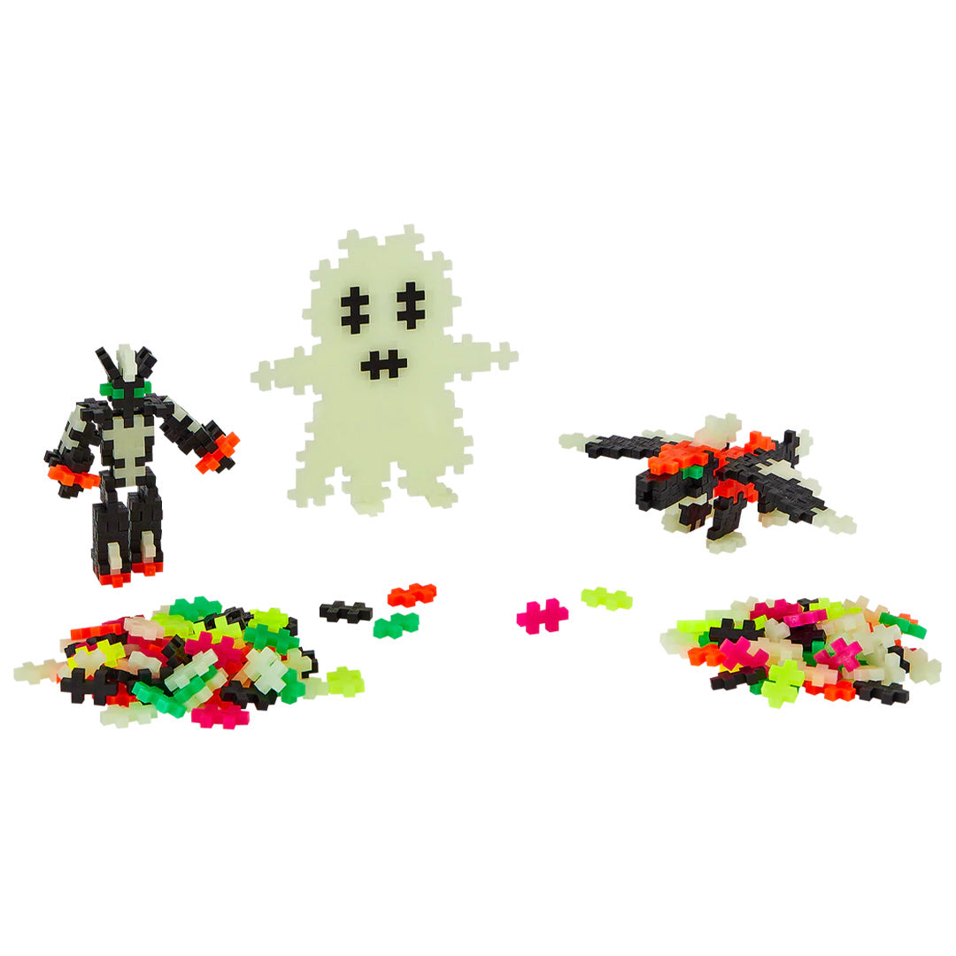 Plus-Plus glow-in-the-dark bouwblokken met een spook, robot en ruimteschip.
