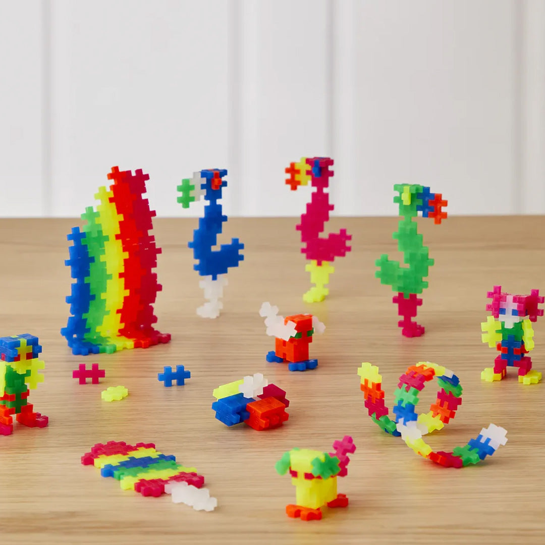 Diverse kleurrijke figuren en vormen gemaakt van Plus-Plus bouwstenen op een houten ondergrond.
