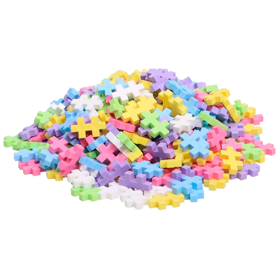 Een grote hoop Plus-Plus pastel bouwblokken op een witte achtergrond.