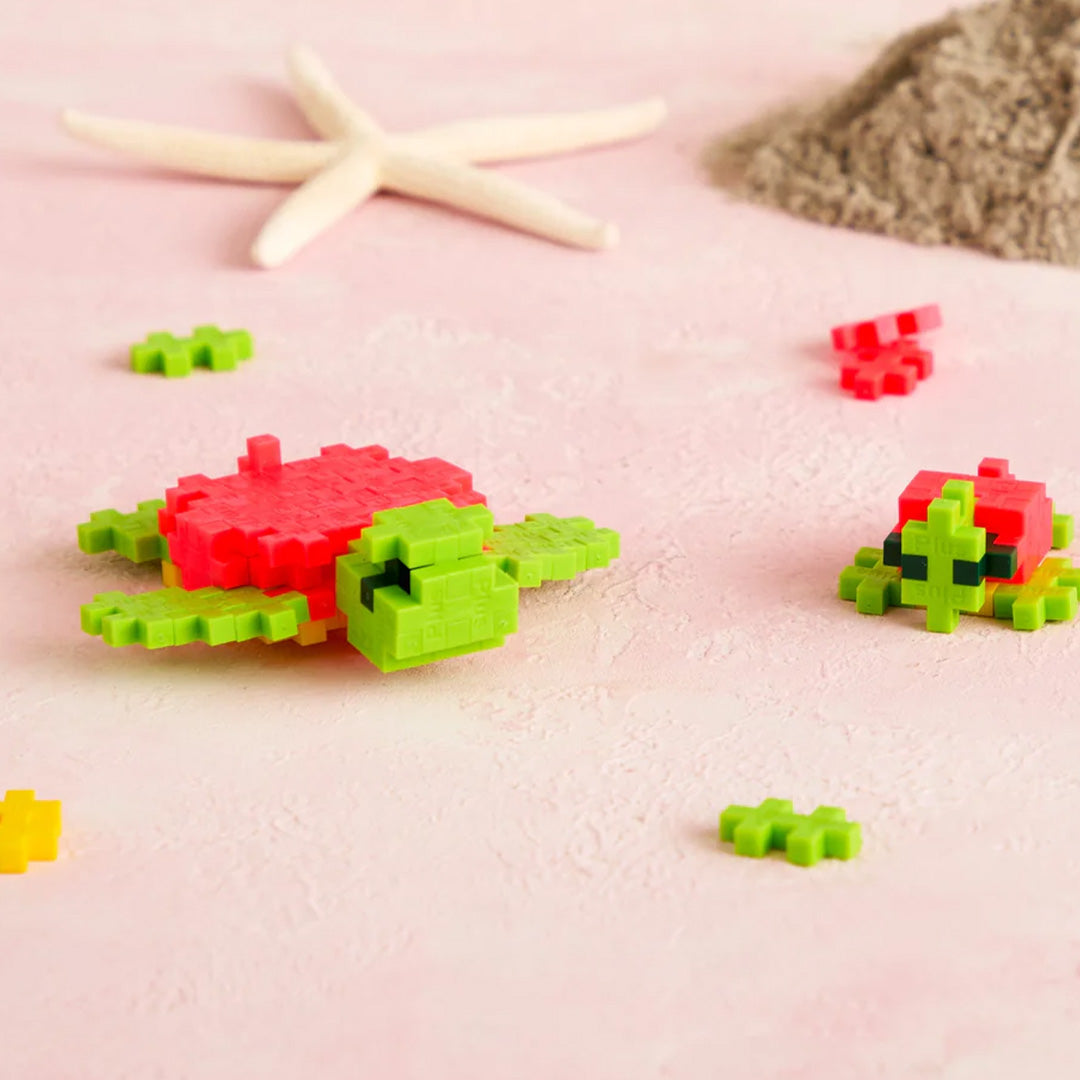Twee Plus-Plus bouwstenen zeeschildpadden, een grote en een kleine, op een roze ondergrond.
