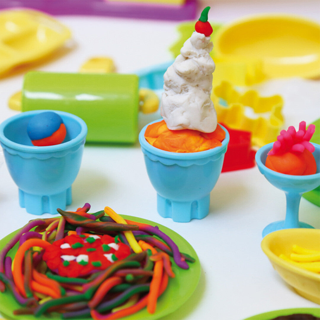 Voorbeelden van snacks gemaakt met de modelleerklei, zoals kleurrijke spaghetti en ijsjes in blauwe bekertjes.