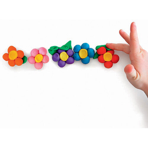 Een kinderhand raakt vijf gekleide bloemen in verschillende kleuren aan.