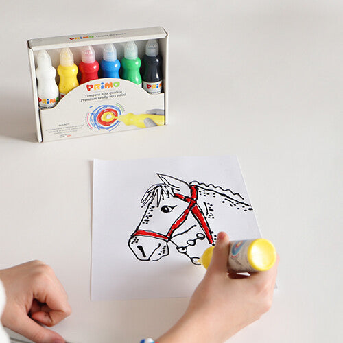 Een kinderhand kleurt een paardentekening in met gele Primo plakkaatverf, met een verpakking met meerdere kleuren op de achtergrond.