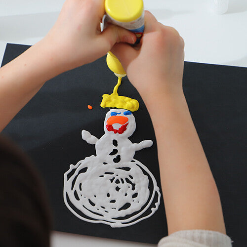 Kinderhanden versieren een sneeuwpoptekening met gele en andere kleuren Primo plakkaatverf op zwart papier.