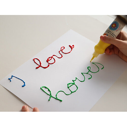 Een kind schrijft 'I love horses' met gele, rode en groene hobbyverf uit knijpflesjes op wit papier.