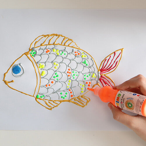 Een hand decoreert een tekening van een vis met oranje Primo plakkaatverf uit een knijpflesje.