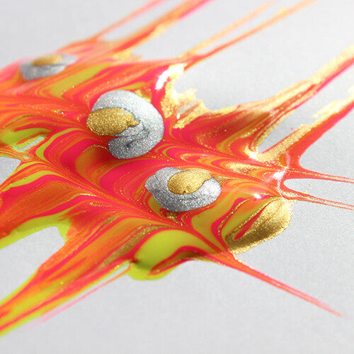 Detail van gemengde oranje, gele, gouden en zilveren verfspatten op een wit oppervlak.