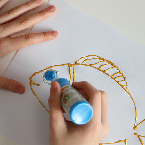 Kinderhanden die blauwe hobbyverf uit een knijpflesje gebruiken om een vis te versieren.