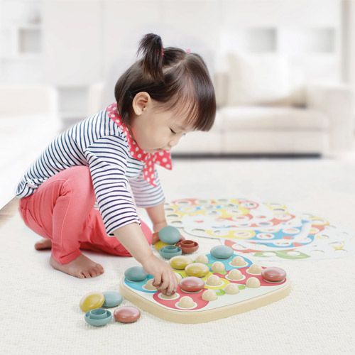 Een kind speelt op de grond met een kleurrijke mozaïekpuzzel voor baby's.