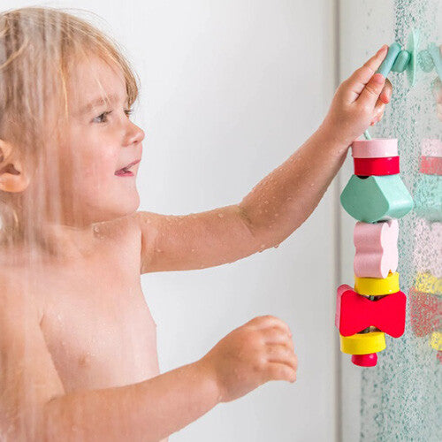 Een kind speelt met de quut rijgkralen badspeelgoed onder de douche.