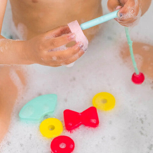 Kinderhanden spelen met de quut rijgkralen badspeelgoed in een bad vol schuim.