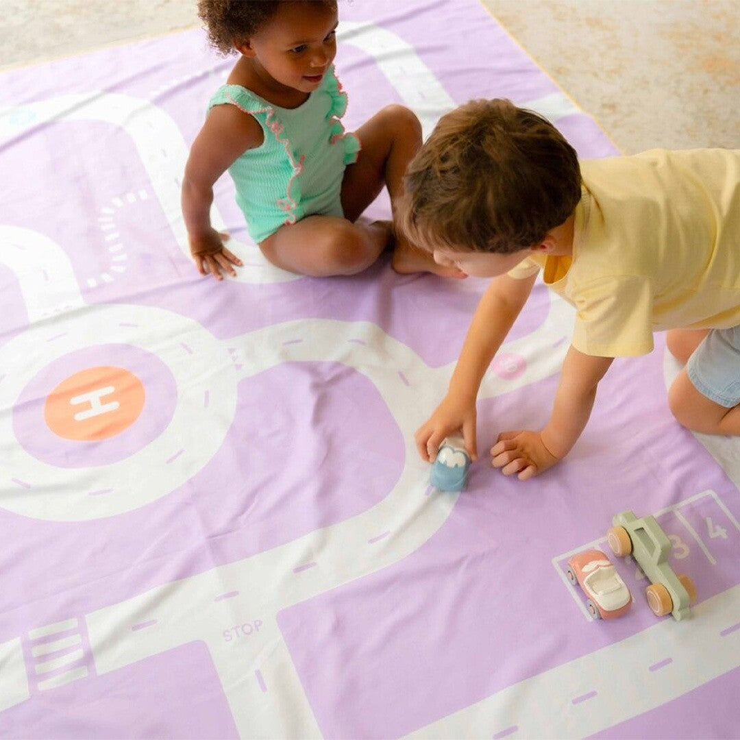Twee kinderen spelen met speelgoedauto's op de paarse quut speelhanddoek met wegenpatroon.