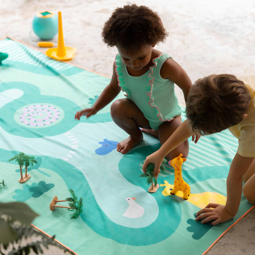 Twee kinderen spelen met speelgoed op de quut groene safari speelhanddoek met dieren en een waterbaan.