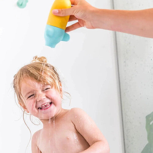 Een lachend kind krijgt water over haar hoofd gegoten met de Quut onderzeeër badsproeier.