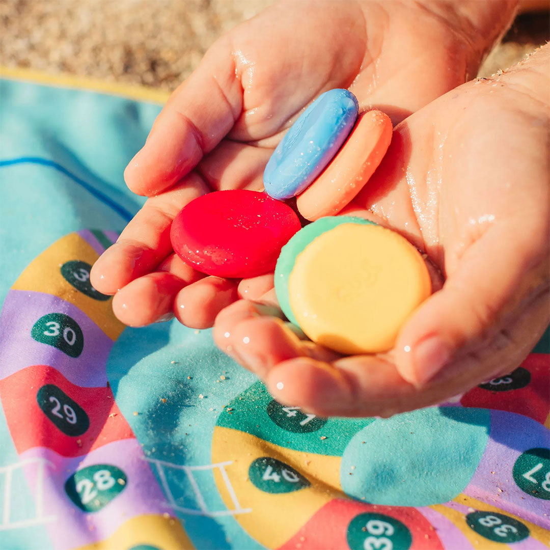 Twee handen houden vier kleurrijke plastic pionnen van het reisspel vast.