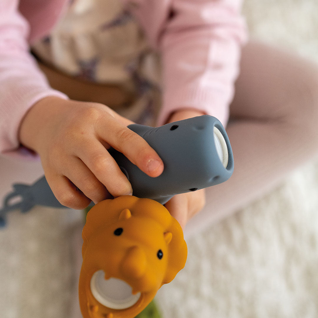 Een kind speelt met de grijze siliconen zaklamp in de vorm van een haai en een oranje olifantenspeeltje.