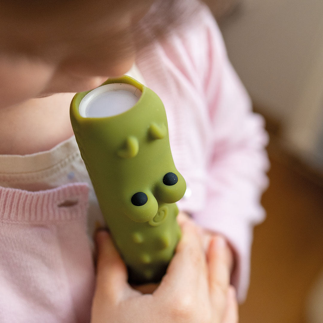 Een kind houdt de groene krokodil zaklamp vast en kijkt in het licht.
