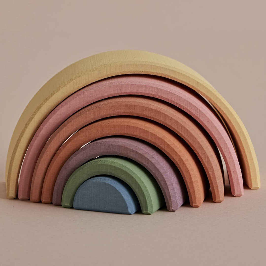 Raduga Grëz houten stapelregenboog in pastelkleuren, schuin van voren gefotografeerd.
