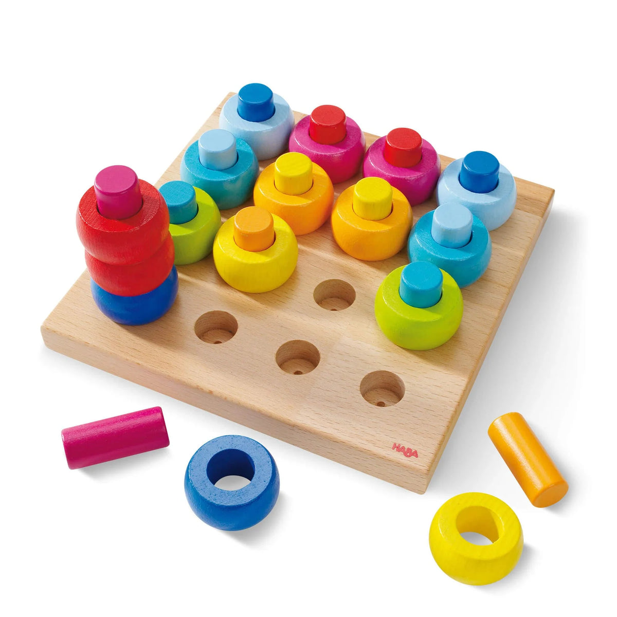 Haba sorteerspel met veelkleurige houten ringen en staafjes op een houten plank.
