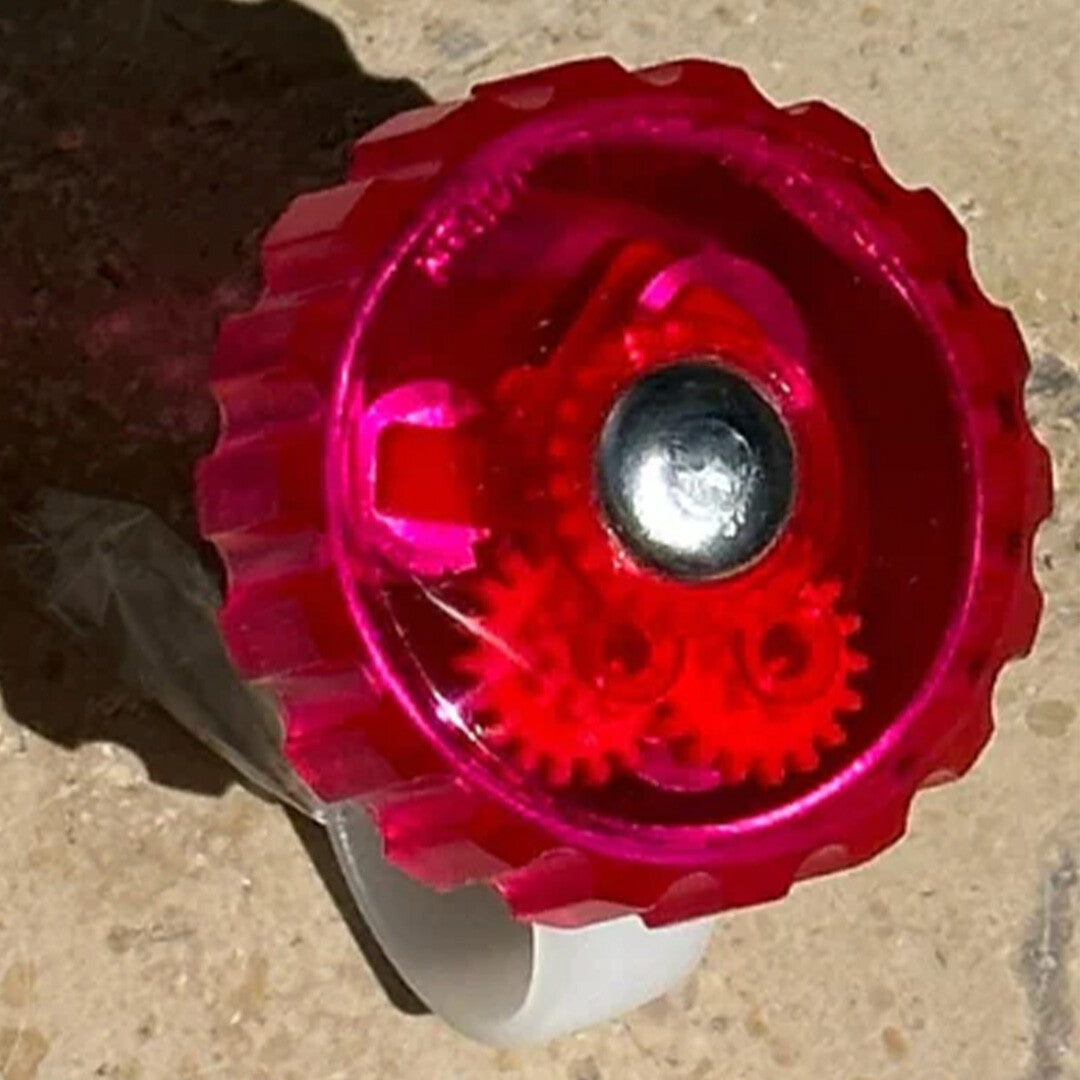 Detailopname van de roze framboise rainette fietsbel met zichtbare tandwielen.