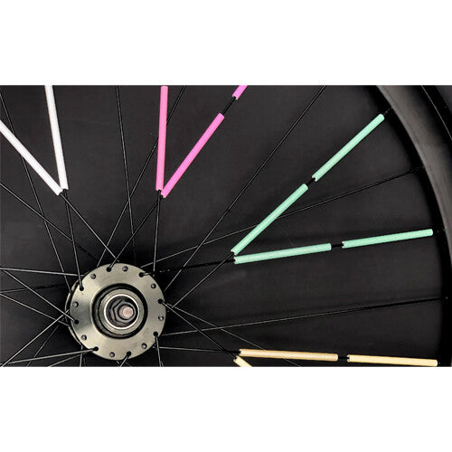 Detail van een fietswiel met rainette spaakreflectoren in metallic wit, roze, mintgroen en goud op de spaken.