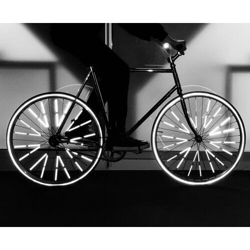 Een fietser in het donker met reflecterende spaakreflectoren op de wielen.