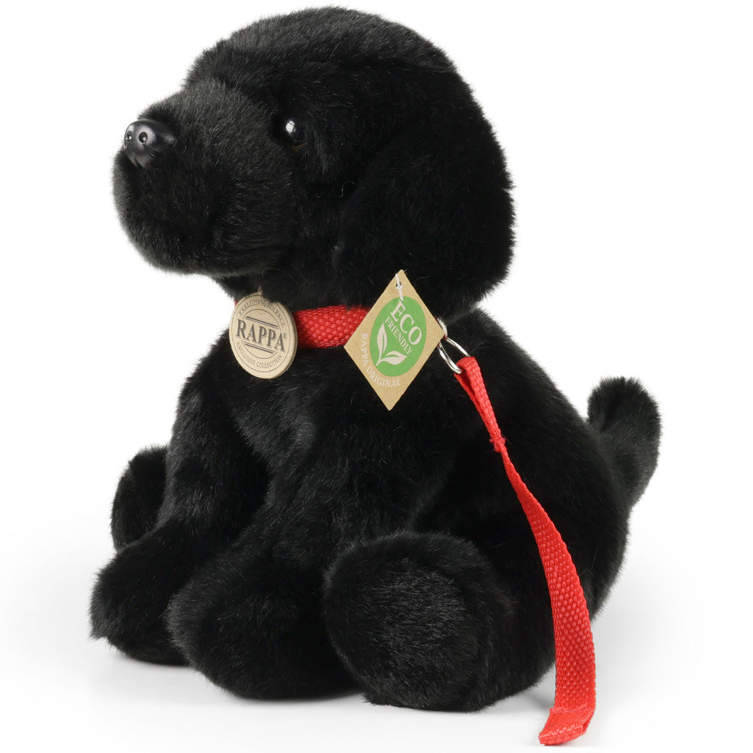 Rappa pluchen Labrador hond met rode halsband en riem, schuin van voren gefotografeerd.